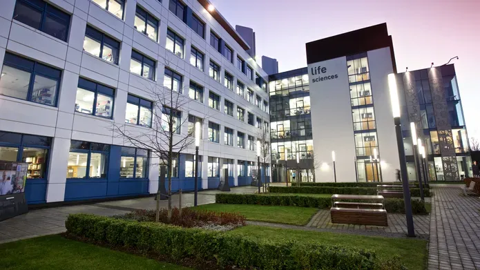View of the Life Sciences Discovery Building at dusk with the lights illuminating the grounds