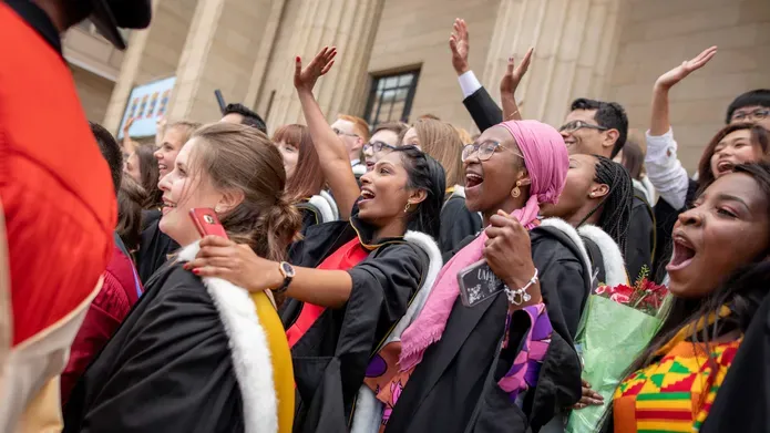 A crowd of students celebrating on the steps of the Caird Hall after the graduation ceremony