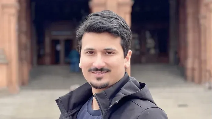 Romail Mukhtar standing outside a red brick building