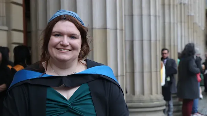 Sophie, dressed in her graduation robes, standing outside the Caird Hall