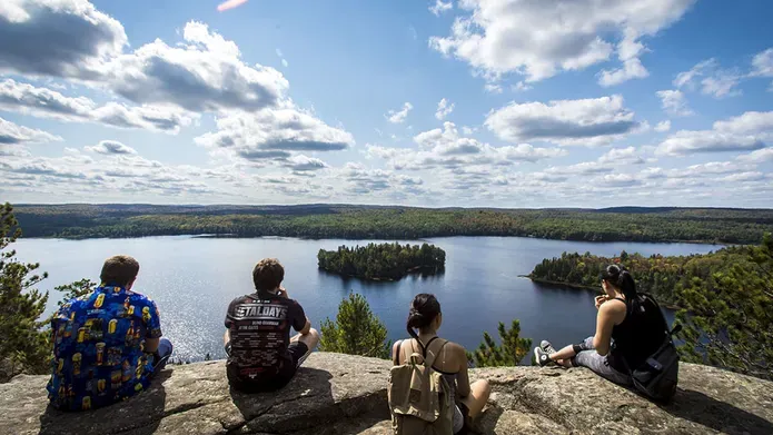 Students sitting on cliff overlooking lake