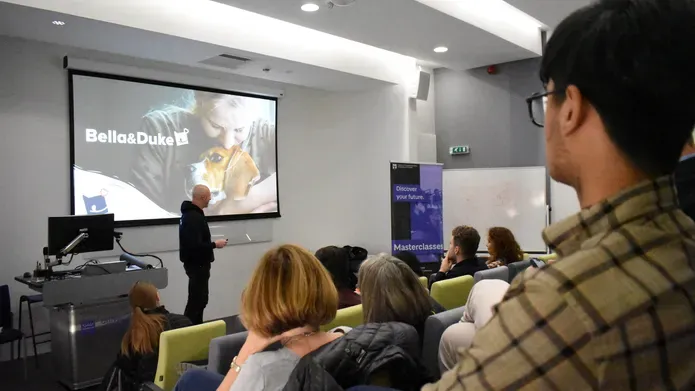 Lecture theatre showing a large screen with Bella&Duke as the heading