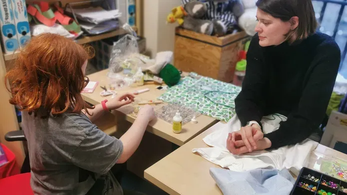 A befriender and young person enjoying a craft session