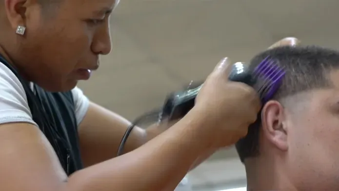 A close up of a  barber shaving a customers hair