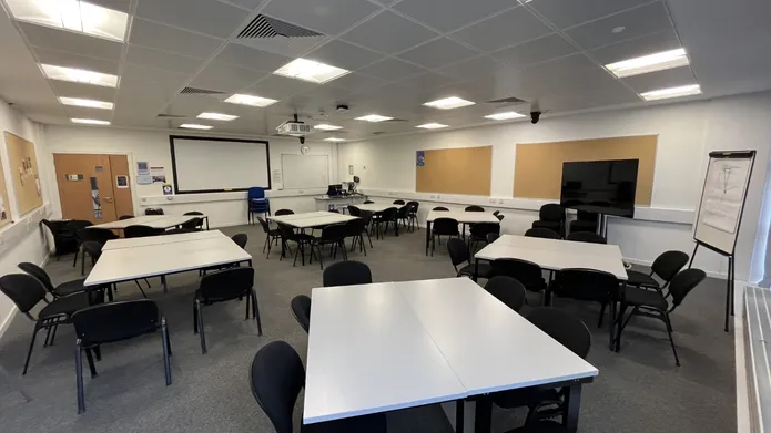 Dalhousie 2F14 - several tables set in squares with chairs and a tv mobile screen and white screen on the wall