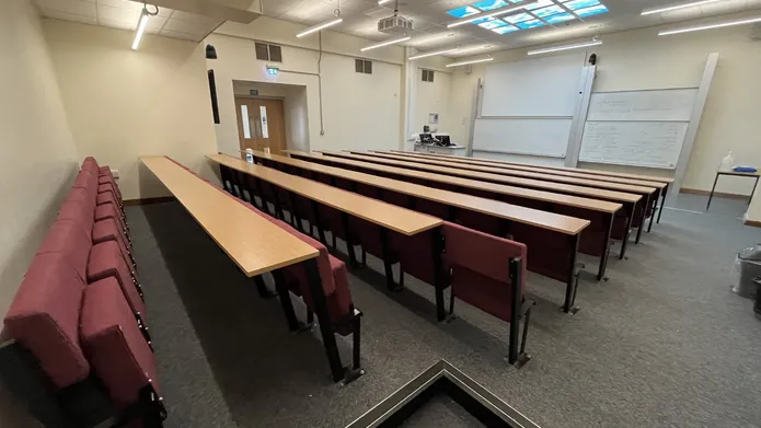 Fulton room J20 with cushioned seats attached to rows and two large white boards at the front of the room