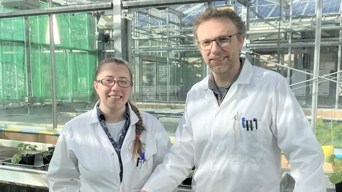 Dr Charlotte Hurst and Dr Piers Hemsley in a glasshouse with seedlings in pots on a table