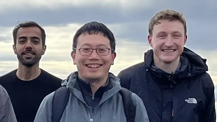 Three men standing next to one another outside on an overcast day