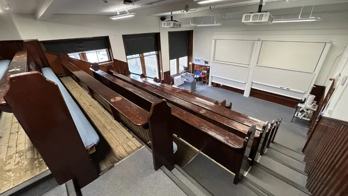 Old Medical School room 2.03 with old wooden benches and two large white screens