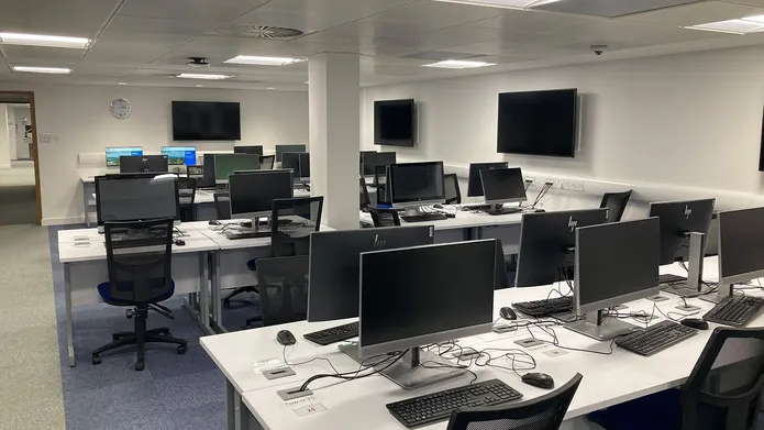 IT Suite in Tower basement showing several desks in rows with computers, mouse and keyboards