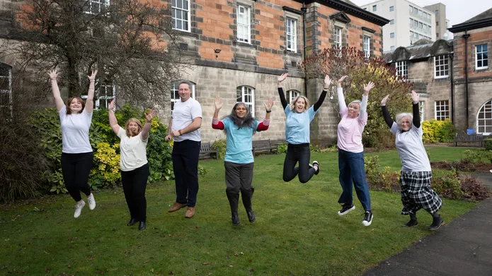 Members of the Playful research group jumping in the air with their hands above their heads set in the Geddes Quadrangle 