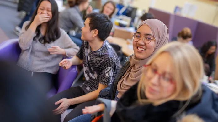 A group of students chatting and laughing in the Global Room