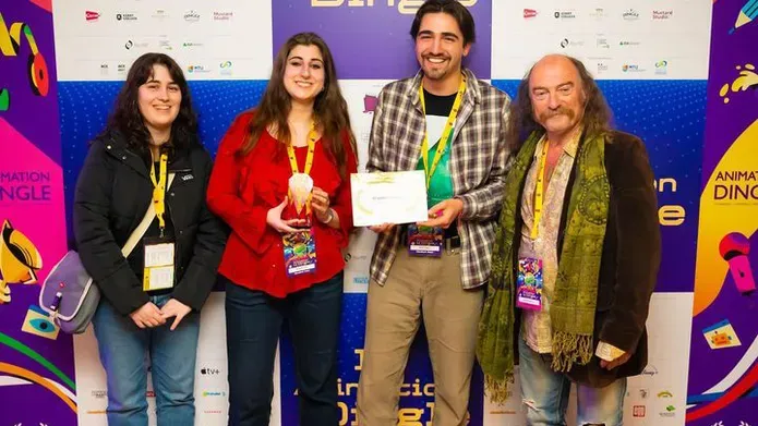 Ariana Glennie, Millie Strachan, Ariyel Feasey who is holding an award and the award presenter standing in front of a billboard for Animation Dingle awards