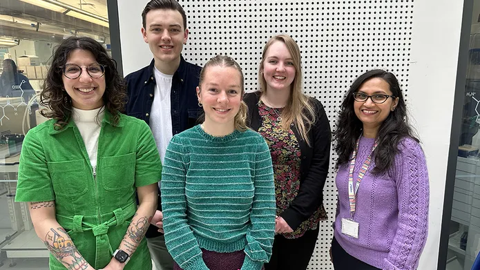 Five people standing in a group, looking towards the camera.