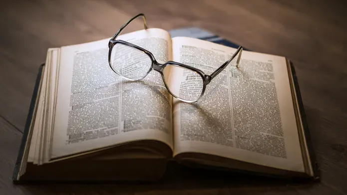photograph of an open book with glasses placed on top