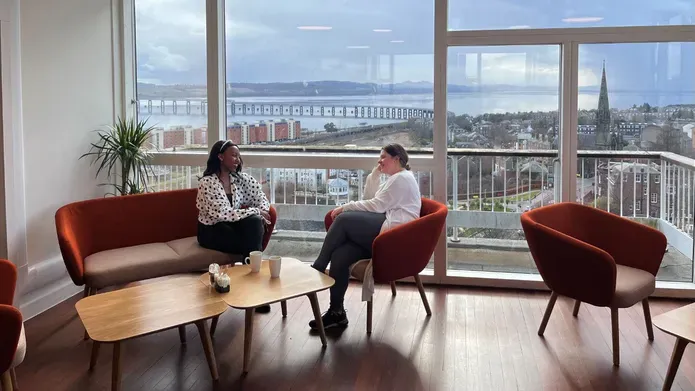  Two people sitting at the window of the Tower cafe with views of the River Tay and rail bridge