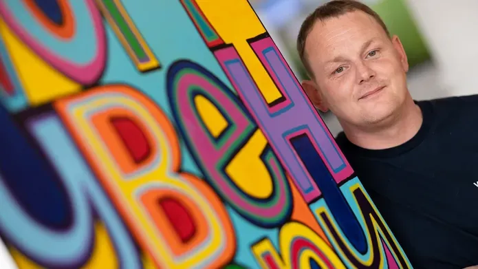 Euan Rutter stood in front of colourful artwork 