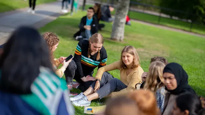 Student sat on the grass at welcome week on campus 