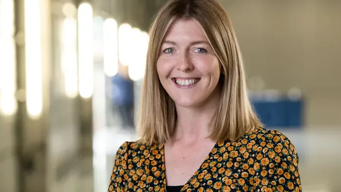 A woman with shoulder length blonde hair smiles at the camera.