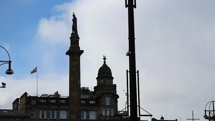 An image of the rooftops of George Square, Glasgow featuring the Walter Scott monument.