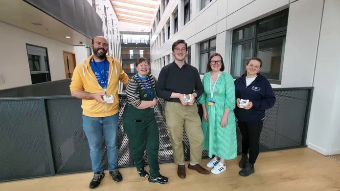 Five people stand on an upper floor of the Life Sciences building, with their backs to a barrier.