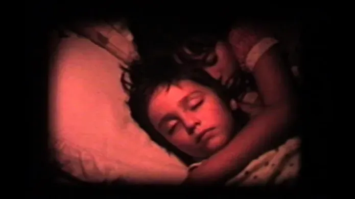 Two sleeping children hugging laying down on a pillow. The shot is in red.