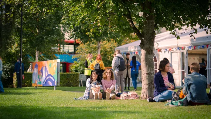 Students sitting on grass at campus green