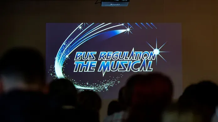 Bus regulation photo showing on a stage in the background 