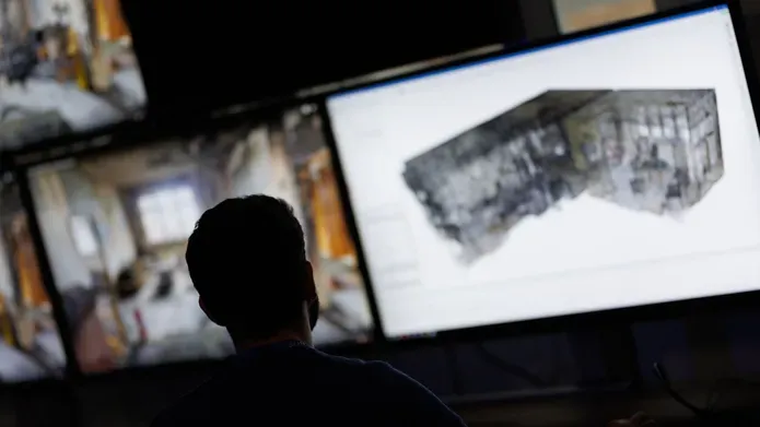 A man looks at multiple computer screens, which are out of focus