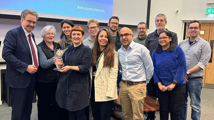 A group of people acceptin an award in front of a projector screen