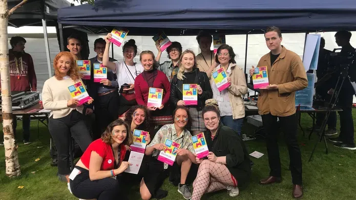 students at a stall holding magazine copies