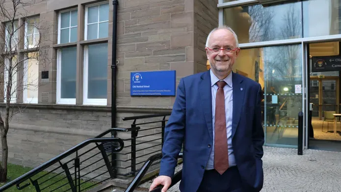 Man wearing a suit standing outside a building wearing a suit, shirt and tie.