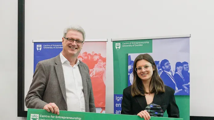 man and woman in suits holding a large green cheque