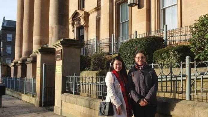 two students outside a stone building with pillars