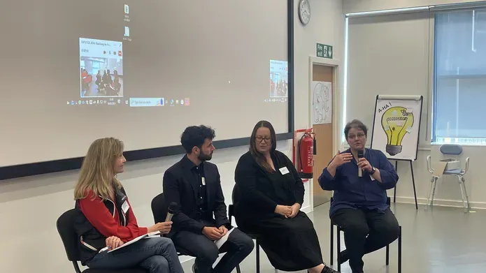 An image of a panel discussion at the meeting. The panel is of 3 women and one man sat on chairs at the front of a lecture theatre