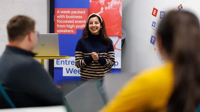 A woman confidently presenting to a group of attentive individuals during a professional meeting.