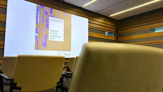 A powerpoint side showing the conference title on a screen in an empty room