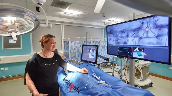 Iris Grunwald standing in an operating theatre looking at a large TV screen