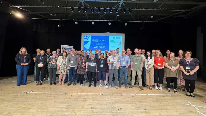 A group of people standing in a large room with a presentation screen in the background