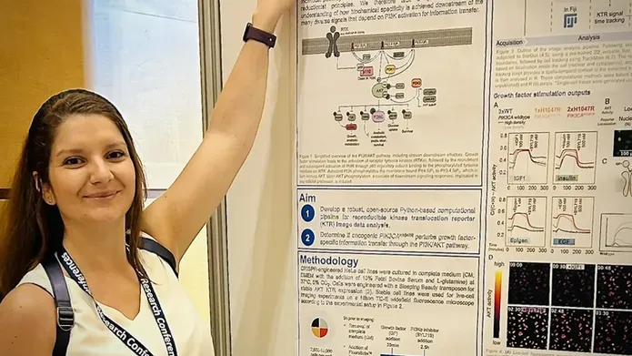 woman in white t-shirt and lanyard pointing at scientific poster