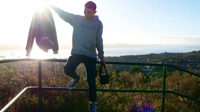 A man sits on metal railing overlooking a viewpoint above the city of Dundee, with the river in the background