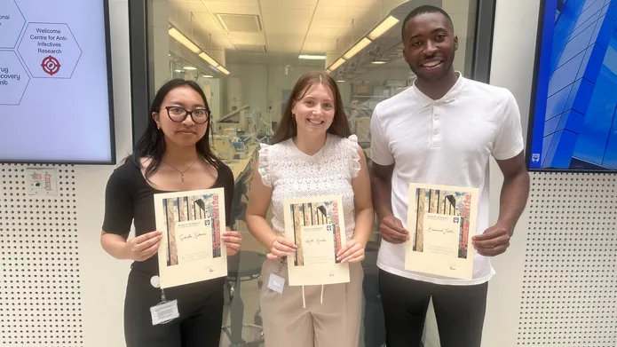 Three people stood next to each other smiling and holding certificates.