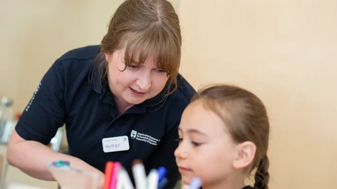 A member of the LRCFS public engagement team aids a child in performing a chromatography experiment