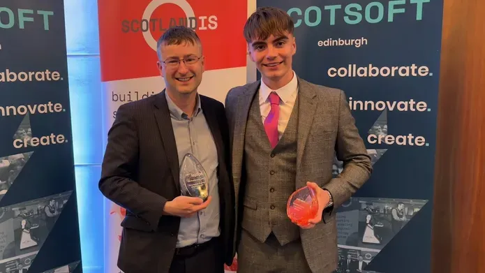 Mike Crabb with David Topping at the ceremony, holding his award before a branded backdrop