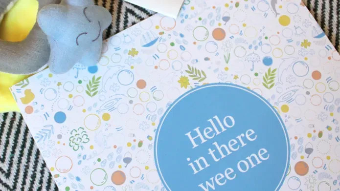 The cover of "Hello In There Wee One", a photo of a baby scan and a baby's rattle