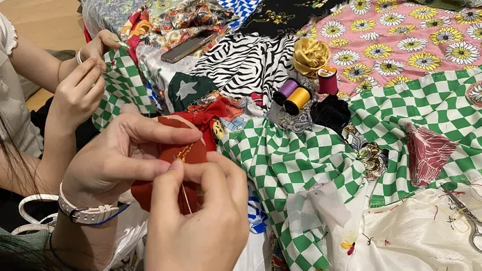 Photo of hands sewing a patchwork of colourful decorative fabrics