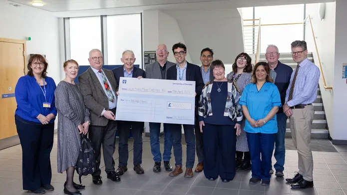 Group photo of Clinical Research Centre staff and Trustees holding a cheque for £50,000