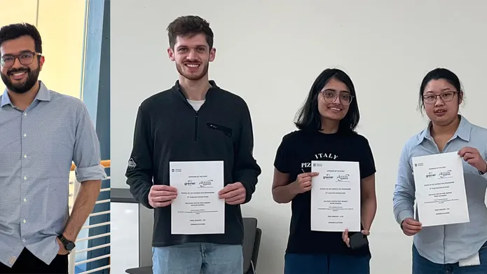 Four people stood smiling. Three holding certificates.