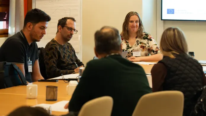 Members of the Clarus project sitting at a table facing each other during a meeting in Oslo, Norway
