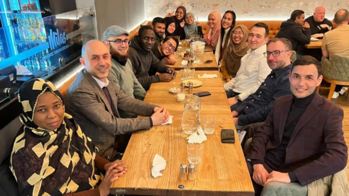 A large group of people sit around a table in a restaurant